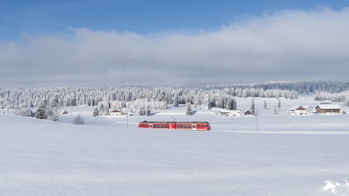 Ein Zug fährt durch eine Schneelandschaft.