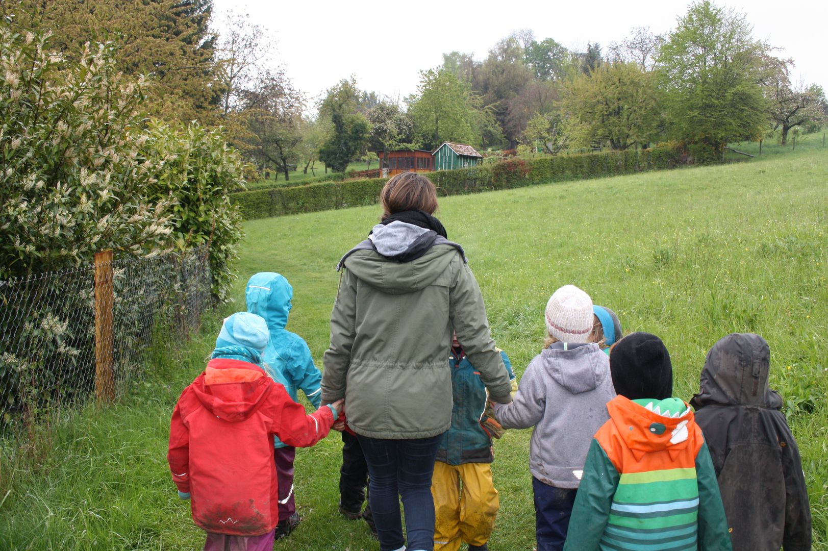 Kindergruppen-Betreuer*in läuft mit Kindern durch die Natur. 