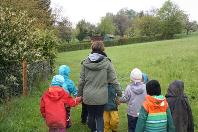 Kindergruppen-Betreuer*in läuft mit Kindern durch die Natur. 