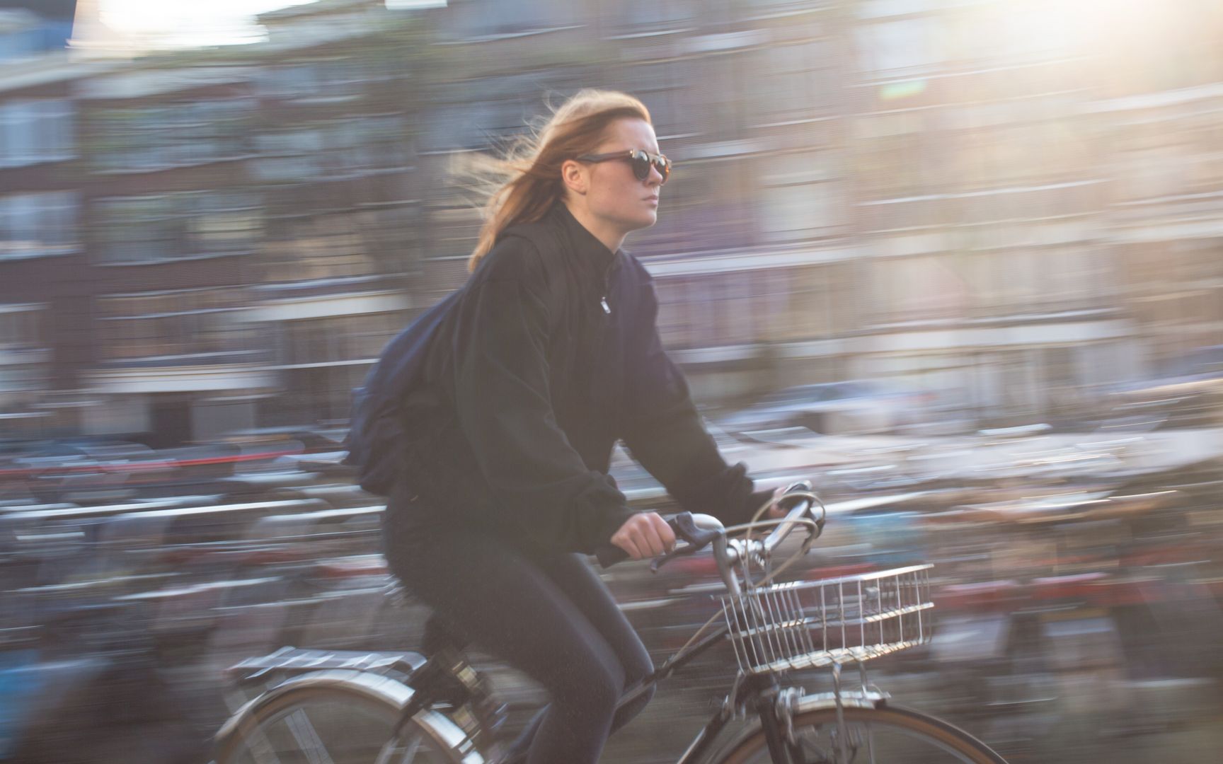 Eine Frau fährt auf einem Fahrrad, die Stadt im Hintergrund verschwimmt durch die Geschwindigkeit