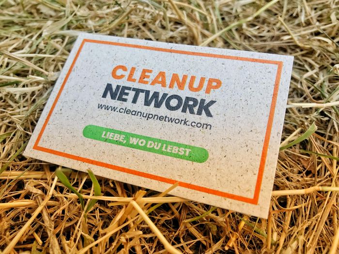 auf Stroh liegender Cleanup Network Flyer mit der Aufschrift "Liebe, wo du lebst"