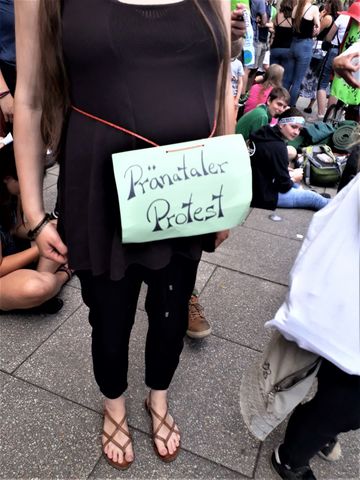 Schwangere Frau mit Schild um Bauch: Pränataler Protest
