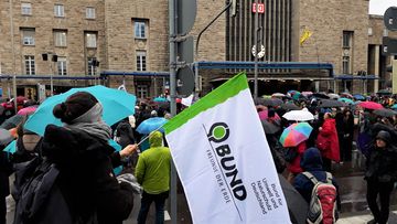 Eine junge Frau hält eine BUND-Fahne inmitten vielen Menschen auf einer Demo vor dem STuttgarter Hauptbahnhof