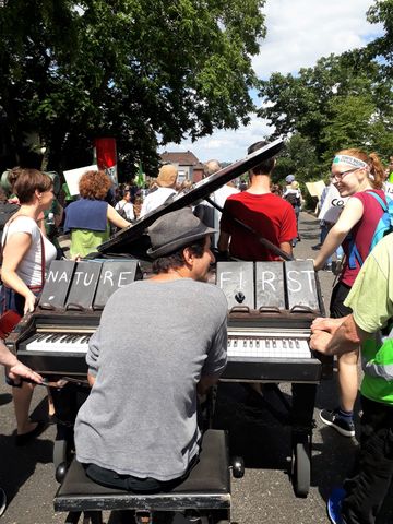 Ein Mann spielt auf einem Klavier, das von anderen Demonstranten geschoben wird