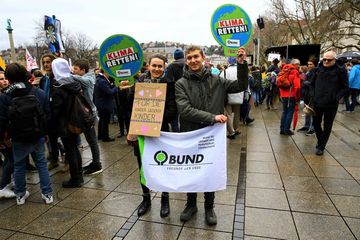Zwei junge Menschen mit BUND Plakaten auf einer Demo.