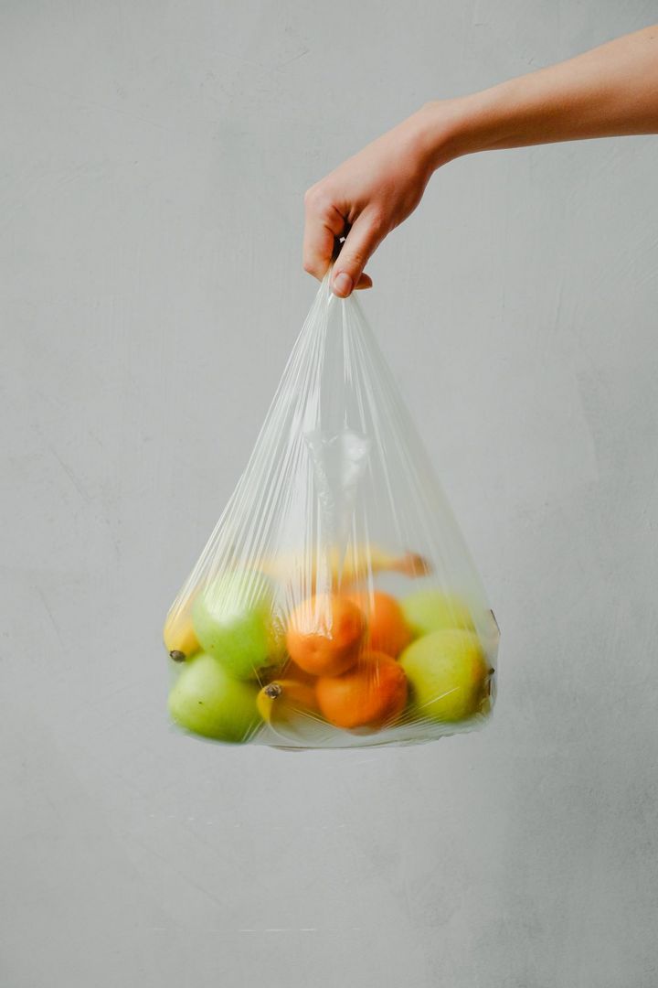 Eine Hand hält eine Plastiktüte mit Obst drin