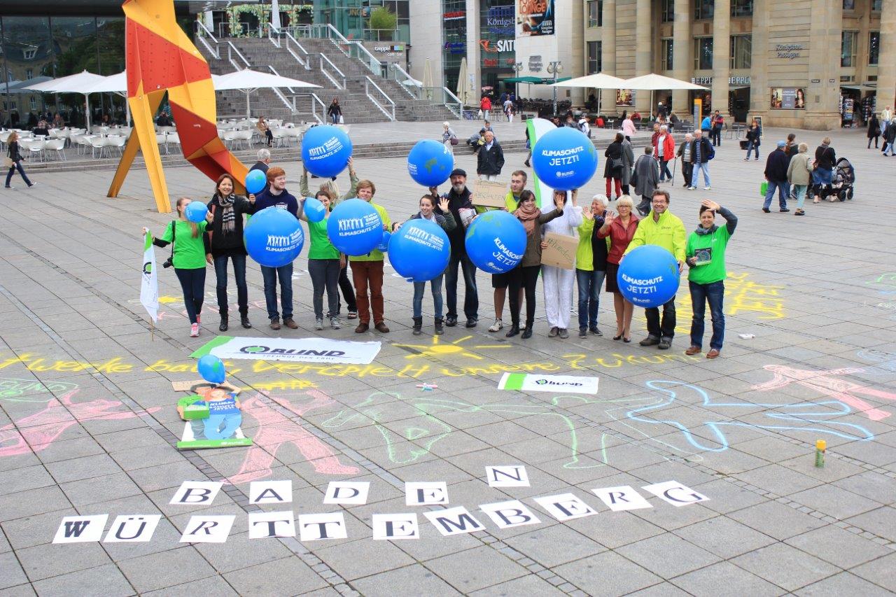 Kreide-Aktion auf dem Stuttgarter Schlossplatz. Menschen halten Luftballons mit dem Aufdruck "Klimaschutz Jetzt". 