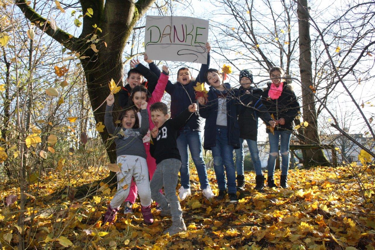 Kinder halten Schild mit der Aufschrift "DANKE" hoch.